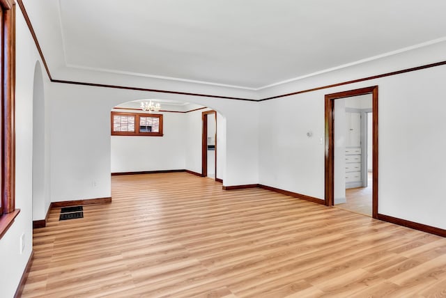 411 W 26th Ave, Spokane, WA 99203 - spare room with arched walkways, a chandelier, crown molding, light wood-style floors, and baseboards