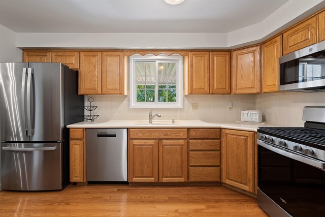 11605 N Merlin Dr, Spokane, WA 99218 - kitchen featuring stainless steel appliances, a sink, backsplash, and light wood finished floors
