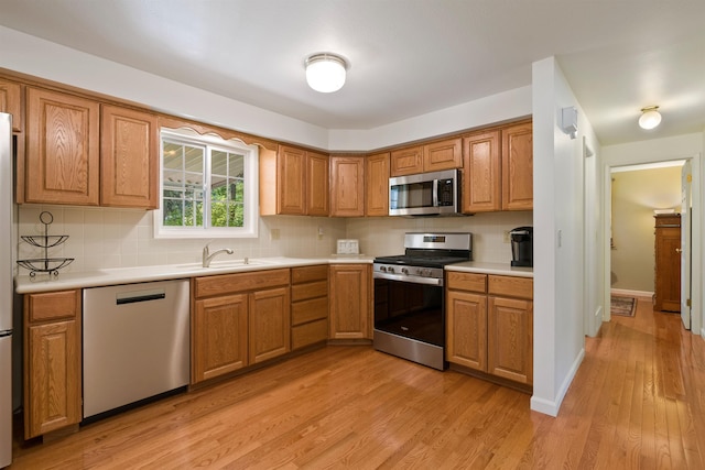 11605 N Merlin Dr, Spokane, WA 99218 - kitchen featuring appliances with stainless steel finishes, brown cabinets, decorative backsplash, light wood-type flooring, and light countertops