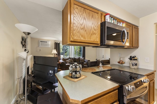202 E Weile Ave Unit 2, Spokane, WA 99208 - kitchen featuring appliances with stainless steel finishes, open floor plan, brown cabinetry, a wall mounted air conditioner, and a brick fireplace