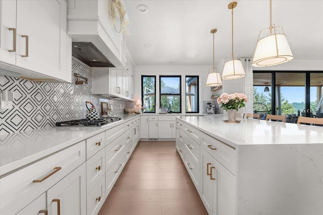 9610 S Mullen Hill Rd, Spokane, WA 99224 - kitchen with stainless steel gas stovetop, custom exhaust hood, decorative backsplash, white cabinetry, and a kitchen island