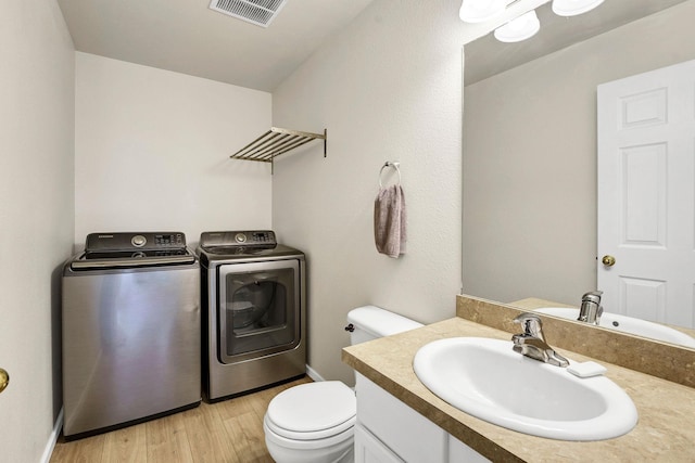 11212 E 4th Ave Unit D, Spokane Valley, WA 99206 - half bathroom with washer and clothes dryer, toilet, vanity, wood finished floors, and baseboards