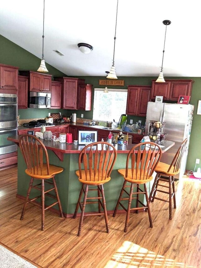 633C Garvey Rd, Colville, WA 99114 - kitchen featuring appliances with stainless steel finishes, a spacious island, dark countertops, light wood finished floors, and a kitchen breakfast bar