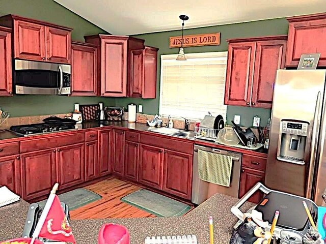 633C Garvey Rd, Colville, WA 99114 - kitchen with stainless steel appliances, pendant lighting, light wood-style floors, reddish brown cabinets, and lofted ceiling