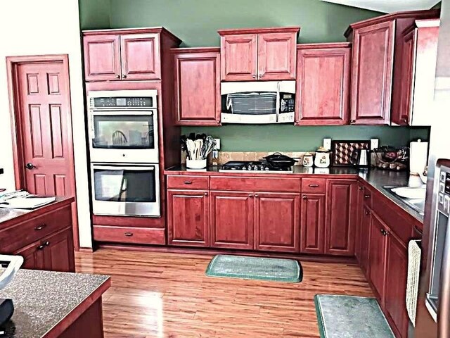 633C Garvey Rd, Colville, WA 99114 - kitchen featuring stainless steel appliances, dark countertops, light wood finished floors, and vaulted ceiling
