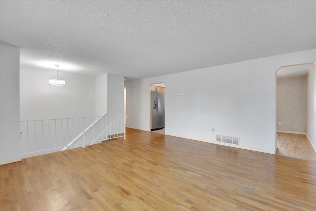 1517 E Olympic Ave, Spokane, WA 99207 - empty room with light wood-type flooring, a textured ceiling, baseboards, and arched walkways