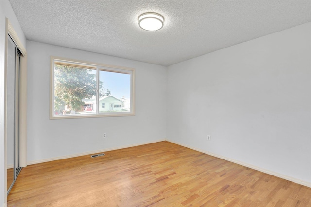 1517 E Olympic Ave, Spokane, WA 99207 - unfurnished bedroom with light wood-style flooring, a textured ceiling, a closet, and baseboards