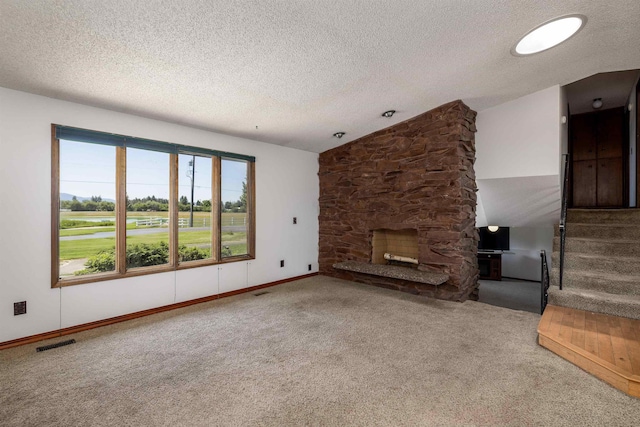 24615 E Joseph Ave, Otis Orchards, WA 99027 - unfurnished living room featuring carpet floors, a textured ceiling, a stone fireplace, lofted ceiling, and stairs