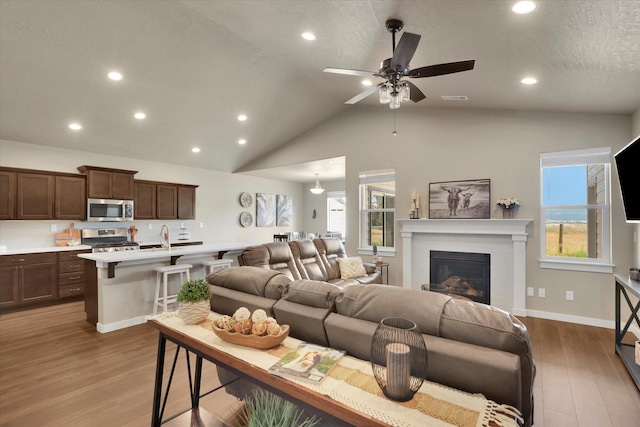 18381 E 17th Ave, Greenacres, WA 99016 - living area with wood finished floors, lofted ceiling, recessed lighting, a ceiling fan, and a fireplace