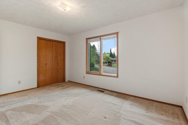 1621 E 65th Ave, Spokane, WA 99223 - unfurnished bedroom featuring a closet, light carpet, and a textured ceiling
