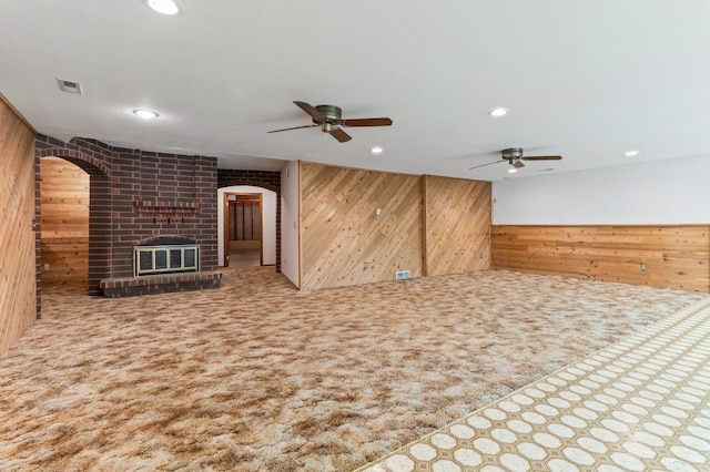 1621 E 65th Ave, Spokane, WA 99223 - unfurnished living room with wooden walls, ceiling fan, a brick fireplace, recessed lighting, and arched walkways