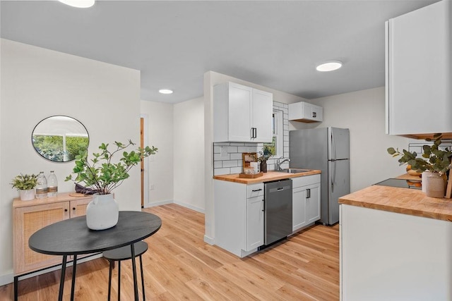 1501 N Lily Rd, Spokane, WA 99212 - kitchen with appliances with stainless steel finishes, butcher block countertops, light wood-style floors, white cabinets, and tasteful backsplash