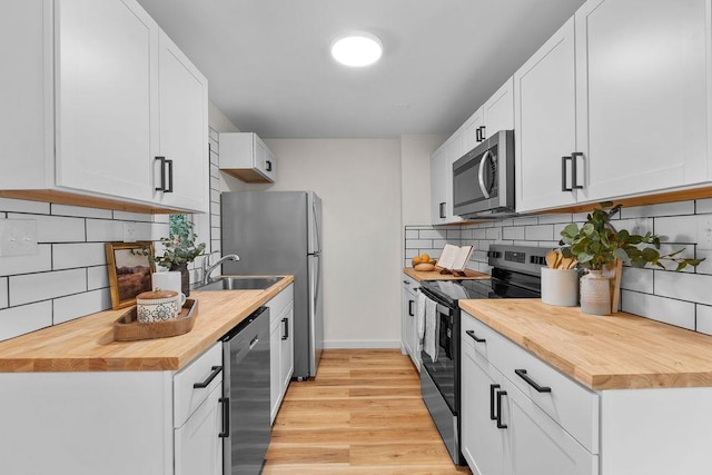 1501 N Lily Rd, Spokane, WA 99212 - kitchen with stainless steel appliances, butcher block counters, tasteful backsplash, light wood-style flooring, and white cabinetry