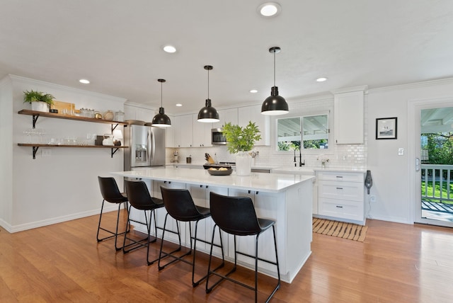 4118 S Stone St, Spokane, WA 99223 - kitchen featuring stainless steel appliances, backsplash, white cabinets, a kitchen breakfast bar, and ornamental molding