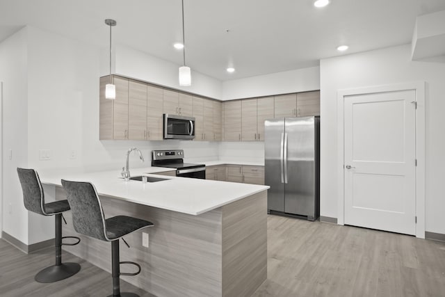 12608 E Nora Ave, Spokane Valley, WA 99216 - kitchen featuring appliances with stainless steel finishes, light wood-style floors, a kitchen breakfast bar, a peninsula, and light countertops