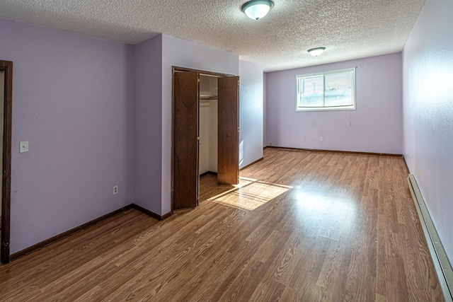 4806 N Drury Rd, Otis Orchards, WA 99027 - unfurnished bedroom with wood finished floors, a closet, a textured ceiling, and a baseboard radiator
