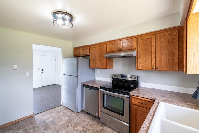 4806 N Drury Rd, Otis Orchards, WA 99027 - kitchen with stainless steel appliances, under cabinet range hood, brown cabinetry, and stone finish flooring