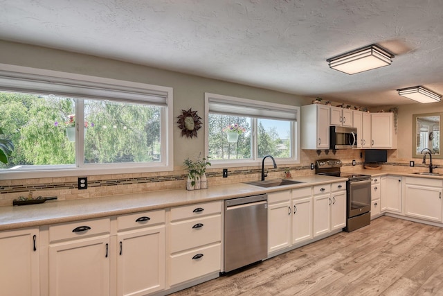 1407 S Shamrock St, Veradale, WA 99037 - kitchen featuring appliances with stainless steel finishes, tasteful backsplash, white cabinets, light wood-style flooring, and light countertops