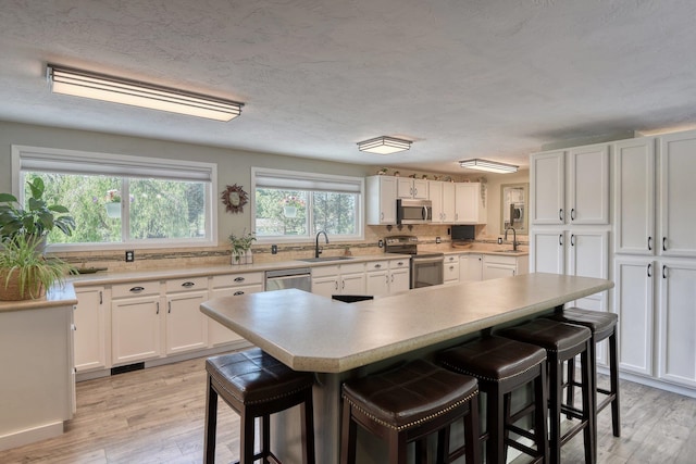 1407 S Shamrock St, Veradale, WA 99037 - kitchen featuring appliances with stainless steel finishes, a kitchen bar, white cabinetry, and light wood finished floors