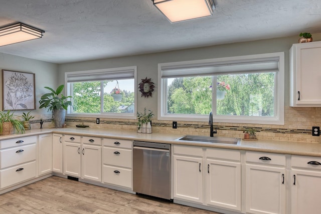 1407 S Shamrock St, Veradale, WA 99037 - kitchen with stainless steel dishwasher, backsplash, white cabinetry, light countertops, and a textured ceiling