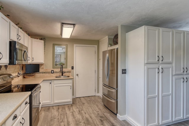 1407 S Shamrock St, Veradale, WA 99037 - kitchen featuring appliances with stainless steel finishes, white cabinets, light countertops, and light wood finished floors