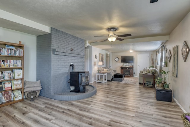 1407 S Shamrock St, Veradale, WA 99037 - living area with a wood stove, wood finished floors, a ceiling fan, and a textured ceiling