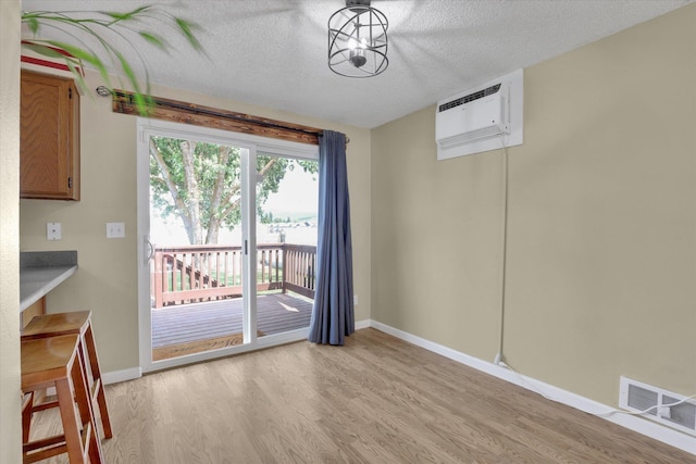 1508 N Arc St, Spokane Valley, WA 99016 - unfurnished dining area with light wood-type flooring, a wall mounted AC, and a textured ceiling