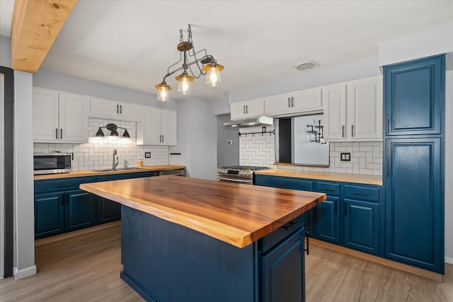 10413 E 6th Ave, Spokane Valley, WA 99206 - kitchen with blue cabinets, butcher block counters, appliances with stainless steel finishes, and decorative backsplash
