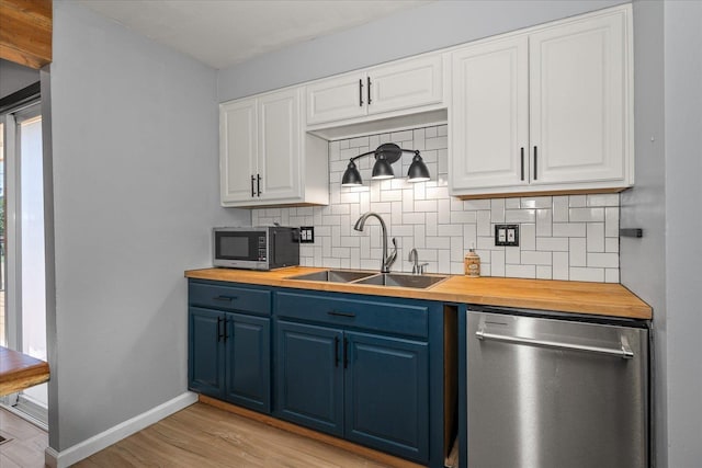 10413 E 6th Ave, Spokane Valley, WA 99206 - kitchen with stainless steel appliances, wooden counters, blue cabinets, decorative backsplash, and light wood-style floors