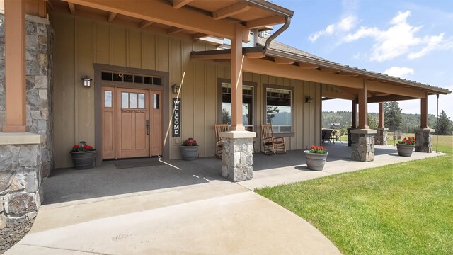 21617 E Harvard Vistas Ln, Newman Lake, WA 99025 - property entrance featuring a porch, board and batten siding, stone siding, and a yard