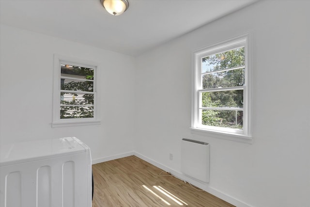 314 E Everett Ave, Spokane, WA 99207 - unfurnished bedroom featuring multiple windows, radiator heating unit, light wood-type flooring, and washer / clothes dryer