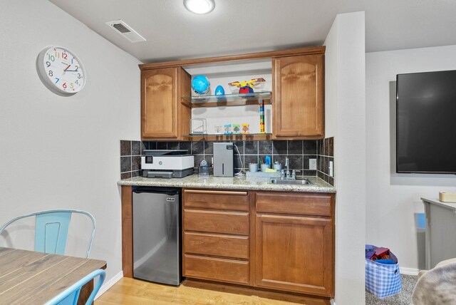 9805 N Jesse Ct, Spokane, WA 99208 - kitchen with backsplash, brown cabinetry, and light wood-style flooring
