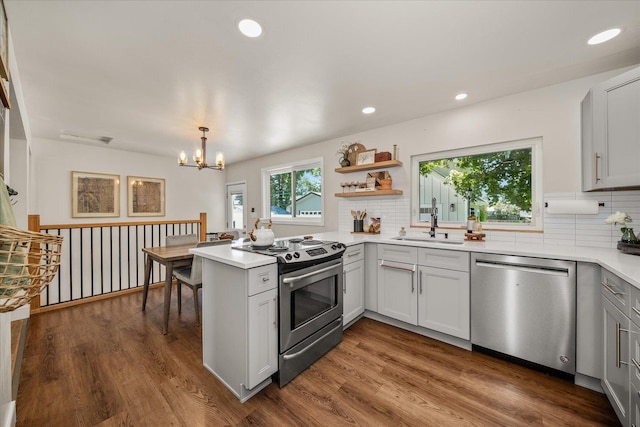 2804 E 39th Ave, Spokane, WA 99223 - kitchen with appliances with stainless steel finishes, a peninsula, tasteful backsplash, light countertops, and a chandelier