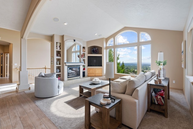 5506 S Southview Ln, Spokane, WA 99223 - living area featuring lofted ceiling, arched walkways, wood finished floors, built in shelves, and a fireplace