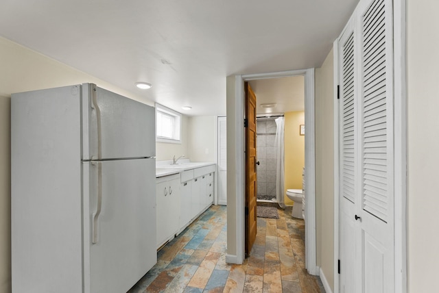 561 E Forest Ave, Colville, WA 99114 - kitchen featuring freestanding refrigerator, stone tile flooring, light countertops, and white cabinets