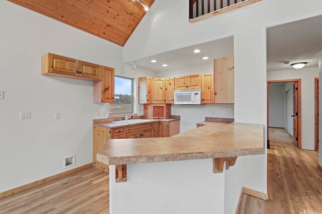 5011B Mason Rd, Clayton, WA 99110 - kitchen with white microwave, light wood-style floors, vaulted ceiling, a peninsula, and a breakfast bar