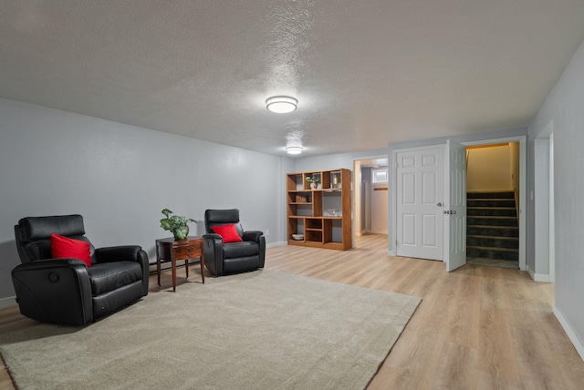 11628 N Galahad Dr, Spokane, WA 99218 - sitting room with light wood-type flooring, a textured ceiling, stairs, and a baseboard heating unit