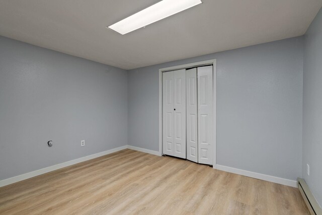11628 N Galahad Dr, Spokane, WA 99218 - unfurnished bedroom with baseboard heating, light wood-style flooring, and a closet