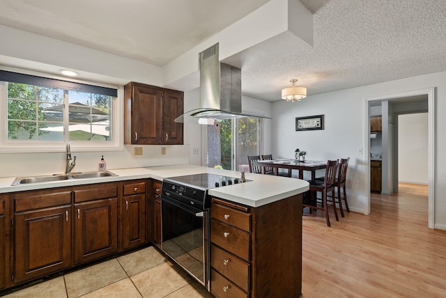11628 N Galahad Dr, Spokane, WA 99218 - kitchen with black / electric stove, wall chimney exhaust hood, a peninsula, light countertops, and plenty of natural light