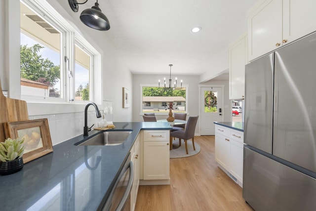 2917 W Dalton Ave, Spokane, WA 99205 - kitchen featuring stainless steel appliances, dark countertops, white cabinetry, light wood-type flooring, and a chandelier