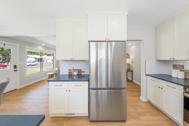 2917 W Dalton Ave, Spokane, WA 99205 - kitchen featuring freestanding refrigerator, dark countertops, decorative backsplash, light wood-style flooring, and white cabinets