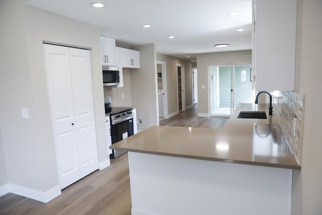 315 E I St, Deer Park, WA 99006 - kitchen with appliances with stainless steel finishes, light wood finished floors, white cabinetry, a peninsula, and decorative backsplash