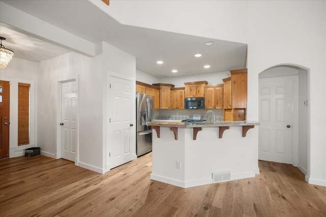 404 W Trail Ridge Ct, Spokane, WA 99224 - kitchen with stainless steel appliances, a breakfast bar area, a peninsula, light wood finished floors, and decorative backsplash