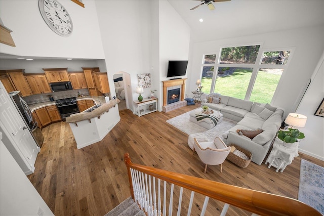 404 W Trail Ridge Ct, Spokane, WA 99224 - living room with high vaulted ceiling, arched walkways, a fireplace, ceiling fan, and light wood-style flooring
