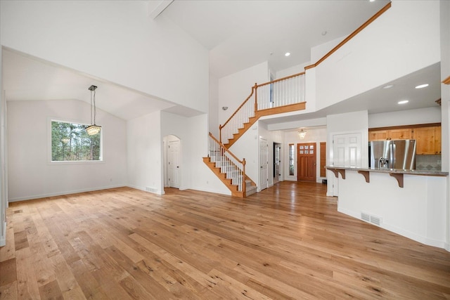 404 W Trail Ridge Ct, Spokane, WA 99224 - unfurnished living room featuring stairway, light wood finished floors, high vaulted ceiling, arched walkways, and recessed lighting