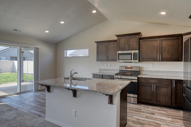 8115 W 57th Ave, Spokane, WA 99224 - kitchen featuring stainless steel appliances, lofted ceiling, light wood-type flooring, a breakfast bar, and light stone countertops