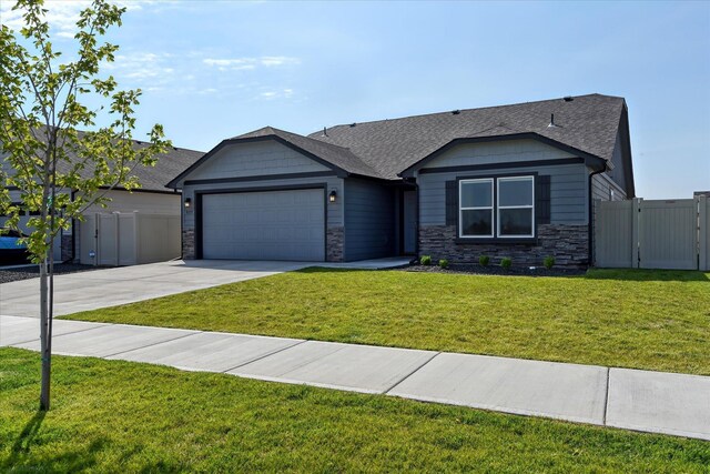 8115 W 57th Ave, Spokane, WA 99224 - view of front of property featuring a garage, concrete driveway, stone siding, a gate, and a shingled roof