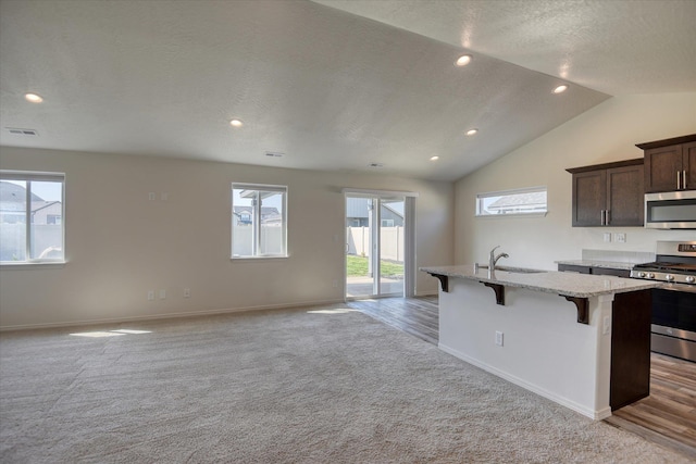 8115 W 57th Ave, Spokane, WA 99224 - kitchen with appliances with stainless steel finishes, light carpet, a center island with sink, a kitchen bar, and open floor plan