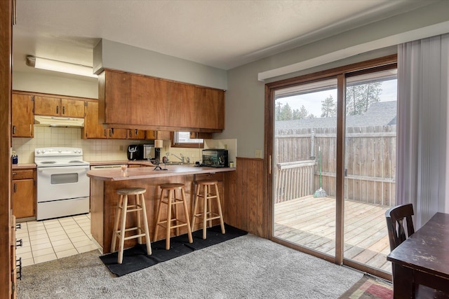 5022 W Garden Springs Ave Unit 5024W, Garden Springs, Spokane, WA 99224 - kitchen with electric range, under cabinet range hood, brown cabinetry, a peninsula, and wainscoting