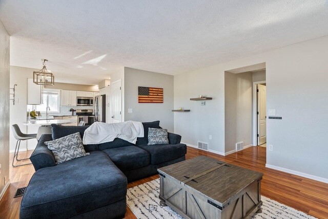 14706 N Mckinnon Ct, Mead, WA 99021 - living room with wood finished floors, a chandelier, and a textured ceiling